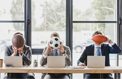 young office workers holding balls while working with laptops in office